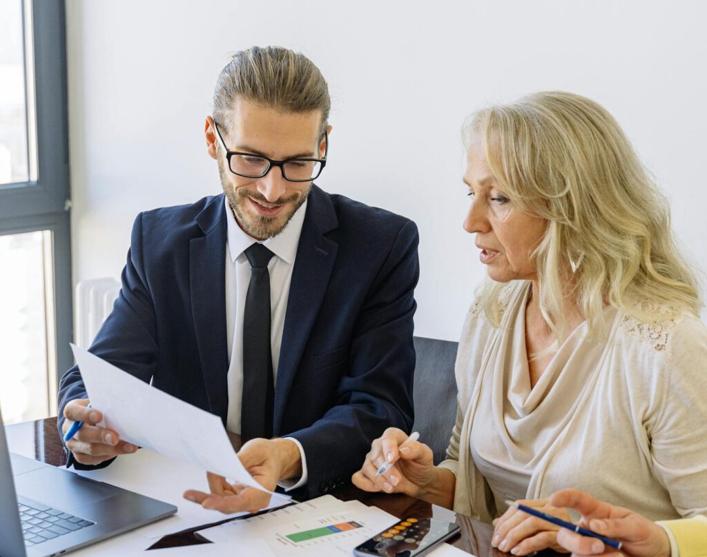 Two business professionals reviewing financial documents and graphs during a meeting.